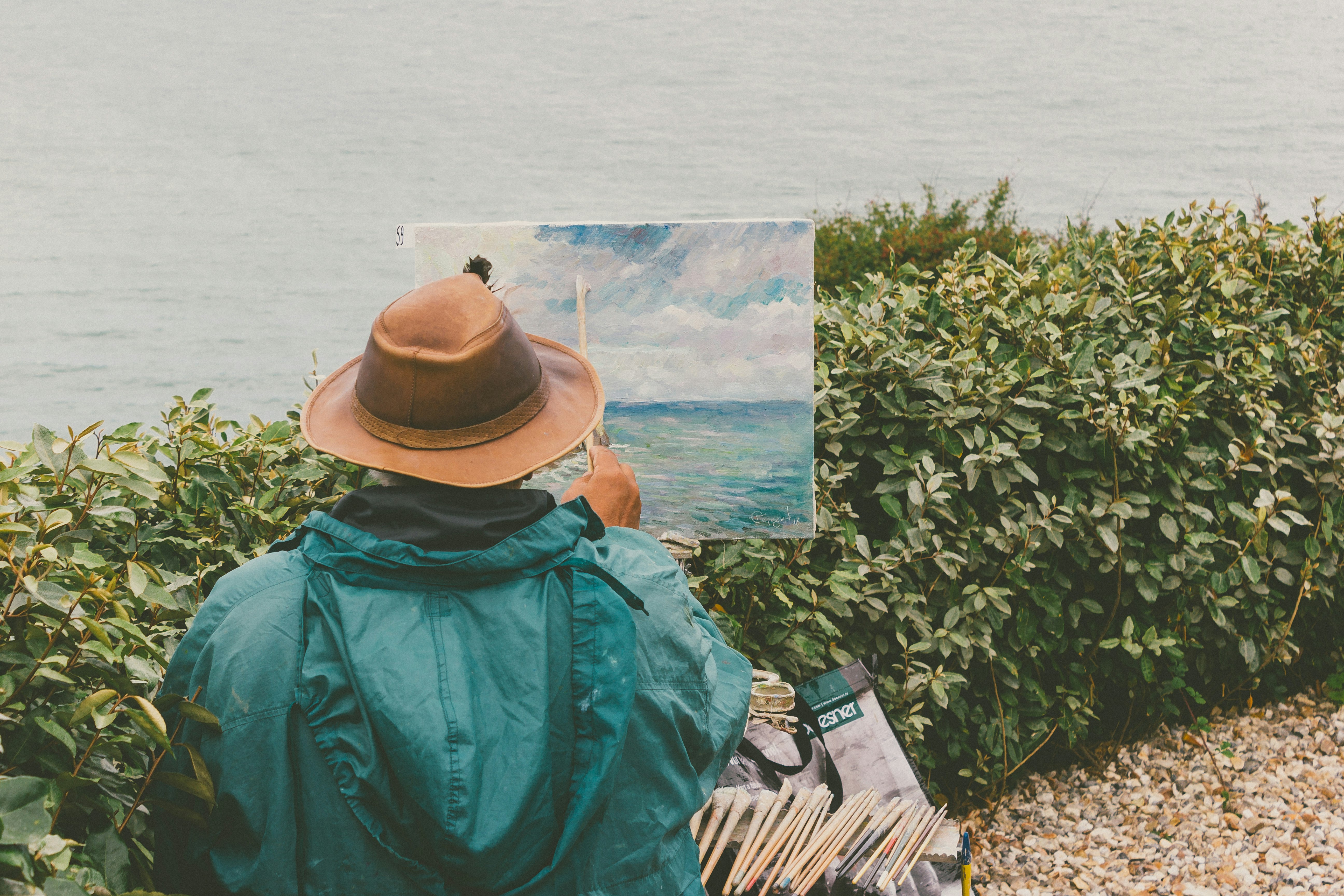 man painting body of water in front of bushes